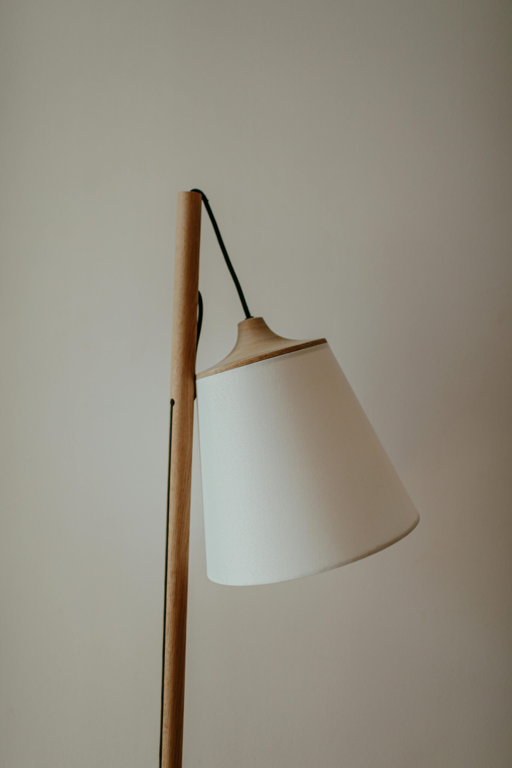 Minimalist wooden floor lamp with white shade against a neutral backdrop, ideal for modern interiors.