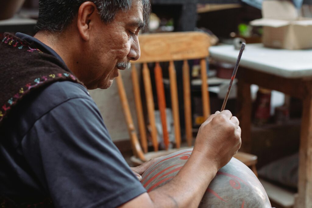 Skilled artisan meticulously paints a traditional ceramic bowl by hand.